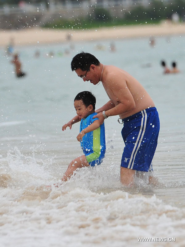 Un homme et son fils s'amusent dans la mer à Sanya, dans la province de Hainan (sud), le 31 décembre 2012. De nombreux touristes se sont rendus à Sanya pour passer le dernier jour de l'année. 