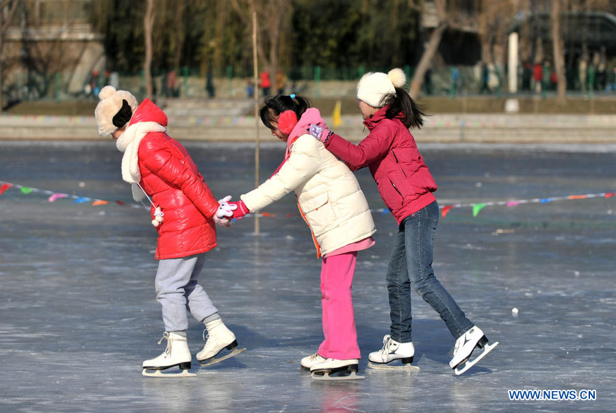 Trois jeunes filles s'amusent à faire du patinage sur le lac gelé au Parc Taoranting, le 3 janvier 2013 à Beijing. (Photo : Li Wen)