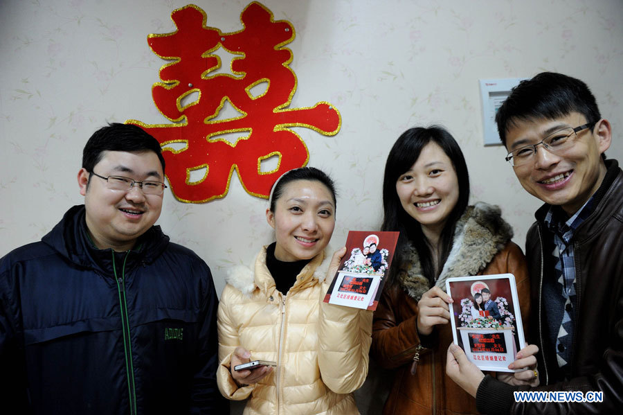 Deux couples montrent leurs photos dans le bureau d'enregistrement des mariages de l'arrondissement de Jiangbei, dans la ville de Chongqing (sud-ouest), le 4 janvier 2013. De nombreux couples ont enregistré leur mariage le 4 janvier 2013, dont la prononciation en chinois ressemble à "je t'aimerai à jamais". (Photo : Li Jian)