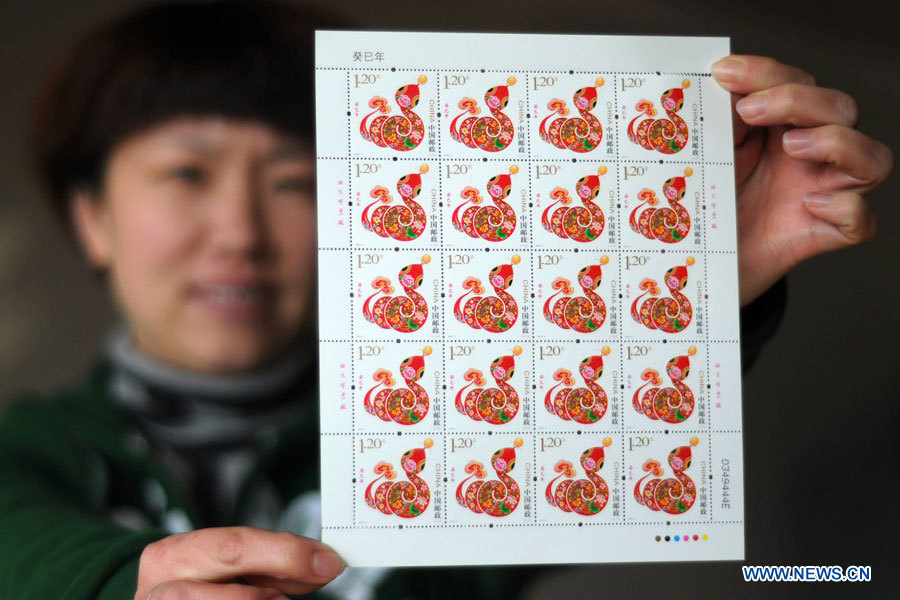 Une employée de la poste de Binzhou, ville de la province du Shandong, montre le timbre de l'année du serpent (2013), le 4 janvier 2013. Ce nouveau timbre sera émis par China Post à partir du 5 janvier.