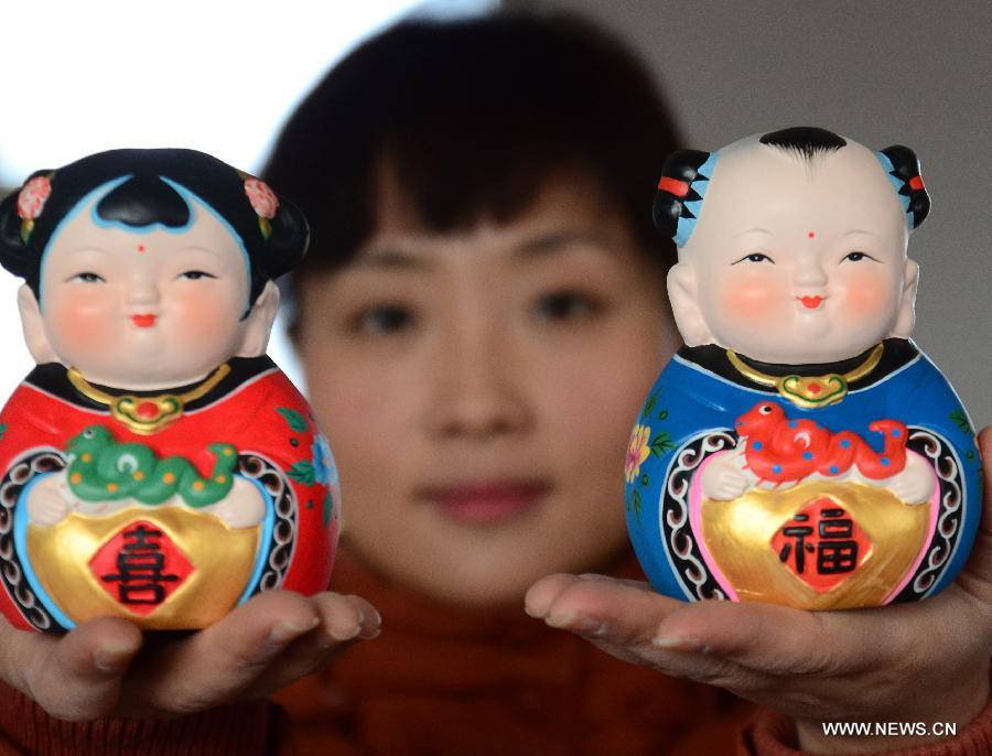 Le 8 janvier 2013 à Sanya dans la province du Hainan en Chine, une artisane montre une petite sculpture en terre glaise traditionnelle chinoise, sur laquelle figure un petit serpent. L'année lunaire 2013 marque « l'année du serpent » du zodiaque chinois. (Xinhua/Chen Wenwu)