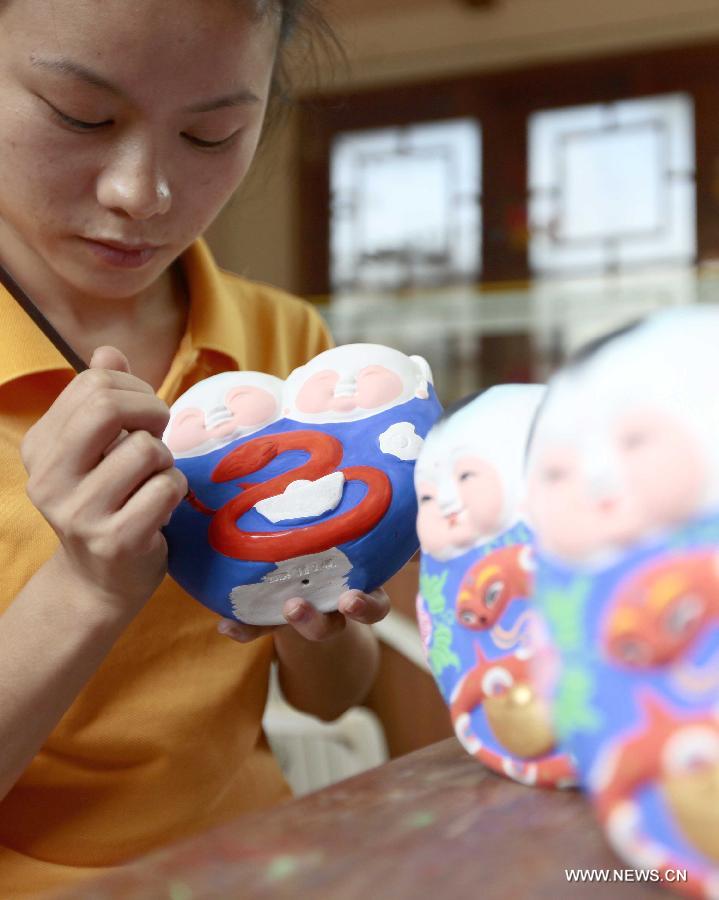 Le 8 janvier 2013 à Sanya dans la province du Hainan en Chine, une artisane façonne de petites sculptures en terre glaise traditionnelles chinoise, sur lesquelles figurent un petit serpent. L'année lunaire 2013 marque « l'année du serpent » du zodiaque chinois. (Xinhua/Chen Wenwu)