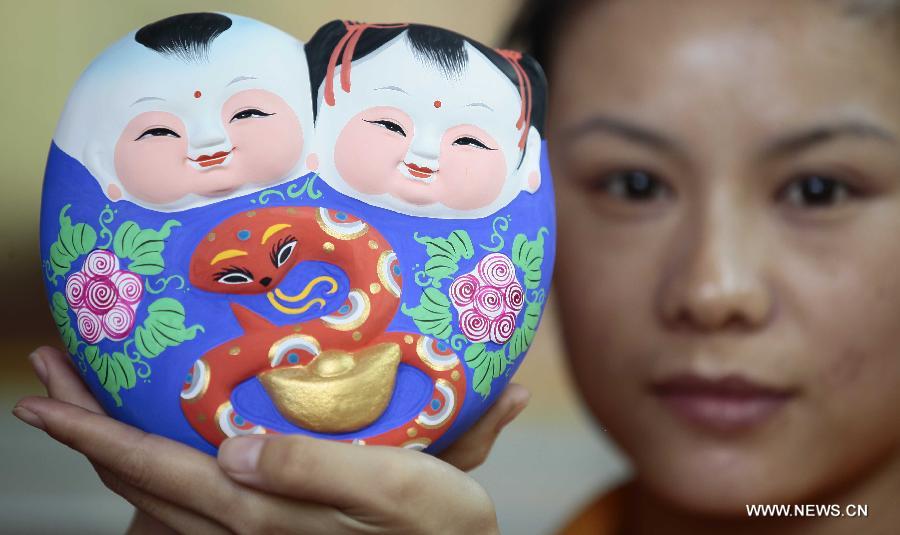 Le 8 janvier 2013 à Sanya dans la province du Hainan en Chine, une artisane montre une petite sculpture en terre glaise traditionnelle chinoise, sur laquelle figure un petit serpent. L'année lunaire 2013 marque « l'année du serpent » du zodiaque chinois. (Xinhua/Chen Wenwu)