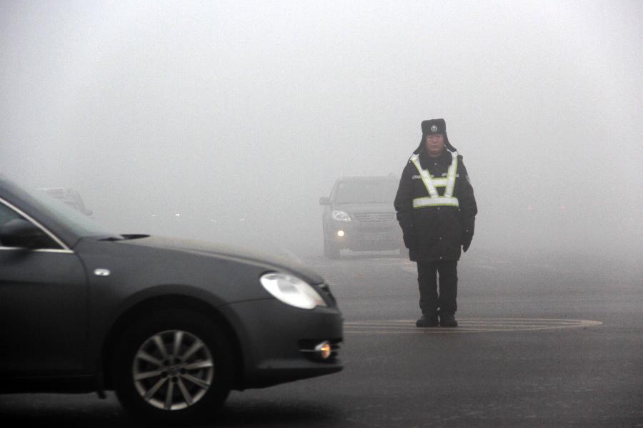 Un agent de la circulation en faction dans le brouillard dans la ville de Bazhou, , dans la Province du Hebei, dans le Nord de la Chine, le 22 janvier 2013. (Xinhua / Wang Geming)