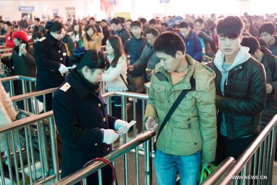 Le 24 janvier 2013, des employés compostent les billets des voyageurs à la gare du nord de Chongqing. A la veille de la Fête du Printemps, de plus en de Chinois se mettent en route pour rentrer chez eux. (Xinhua/Liu Chan)