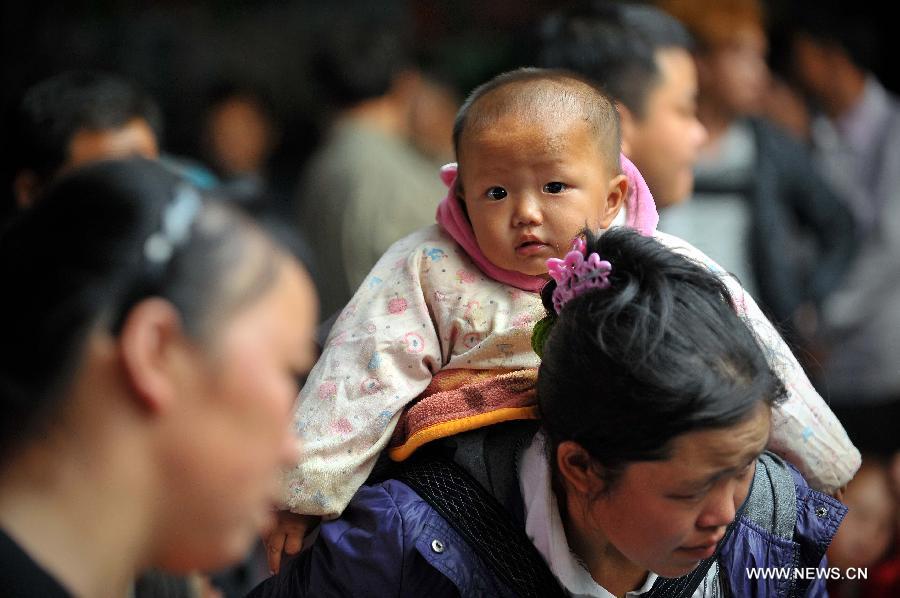 Le 24 janvier 2013, dans le port de Xiuying à Haikou, la capitale de la province chinoise de Hainan Une femme portant un bébé au dos est prête à embarquer.  A l'approche de la Fête du Printemps, la ville a connu ces derniers jours des pics de fréquentation dans les transports. (Xinhua/Guo Cheng)