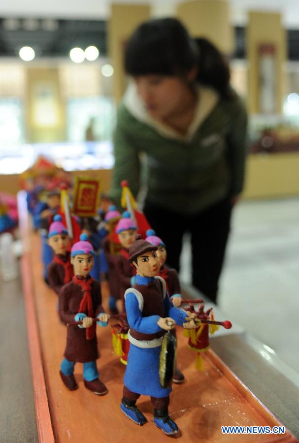 Une visiteuse observe de petites sculptures en terre glaise lors d'une expostition de la culture traditionnelle chinoise ouverte à Shijiazhuang le 28 janvier 2013. (Xinhua/Zhu Xudong)