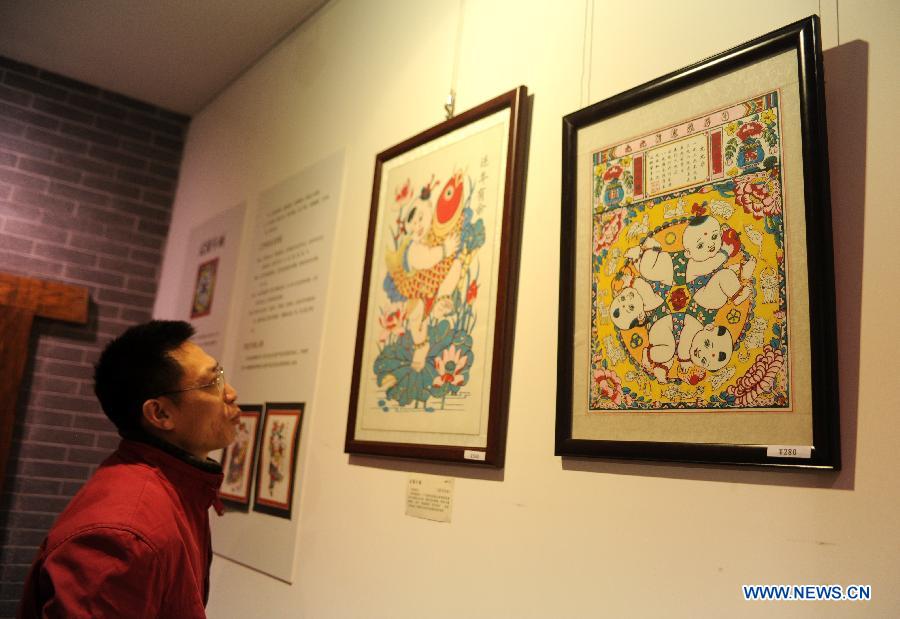 Un visiteur devant des peinture du Nouvel An chinois lors de l'Exposition de la culture traditionnelle chinoise ouverte à Shijiazhuang le 28 janvier 2013. (Xinhua/Zhu Xudong)