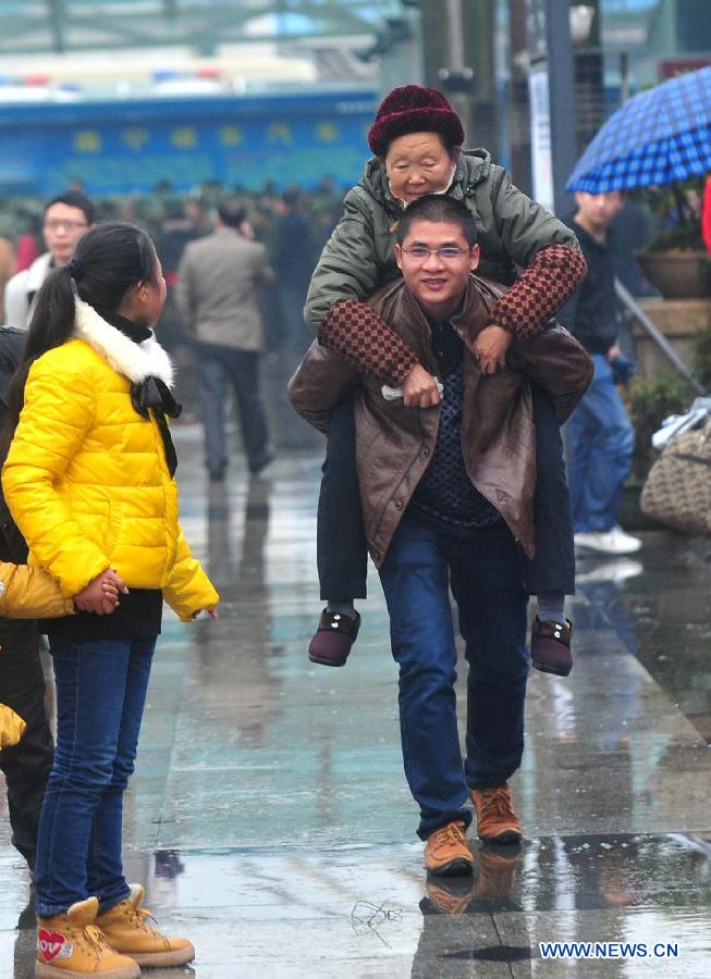 Le 26 janvier 2013, un homme porte sa belle-mère sur son dos et se dirige vers la gare de Nanning, la capitale de la Région autonome Zhuang du Guangxi du sud de la Chine. (Xinhua/Huang Xiaobang)