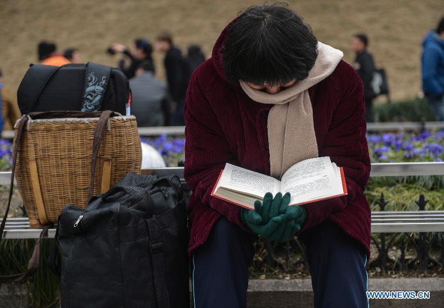 Le 27 janvier 2013, une femme en pleine lecture attend son train sur la place de la gare de Hangzhou, capitale de la province du Zhejiang en Chine. (Xinhua/Han Chuanhao)