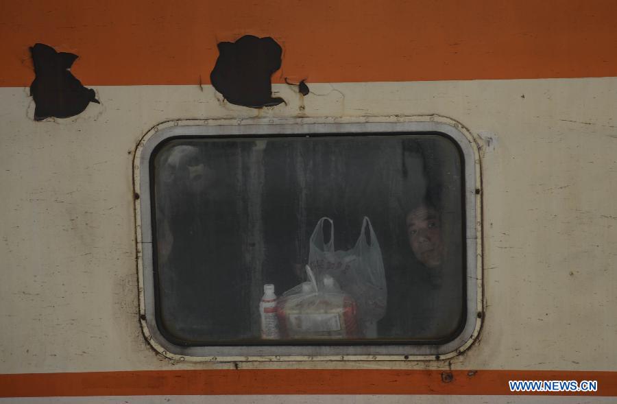 Un passager dans un train, jette un coup d'oeil par la fenêtre, le 27 janvier à la gare de Hangzhou, capitale de la province du Zhejiang en Chine. (Xinhua/Han Chuanhao)