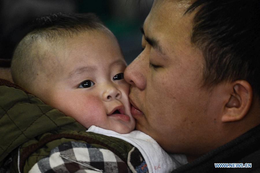 Un père embrasse son bébé en attendant leur train à la gare de Hangzhou le 27 janvier 2013. (Xinhua/Han Chuanhao)