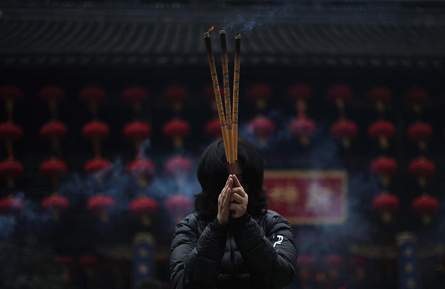 Une femme tient des bâtons d'encens au Temple du dieu protecteur de la ville (Chenghuang Miao) au jardin Yuyuan, dans le centre-ville de Shanghai, le 4 février 2013.