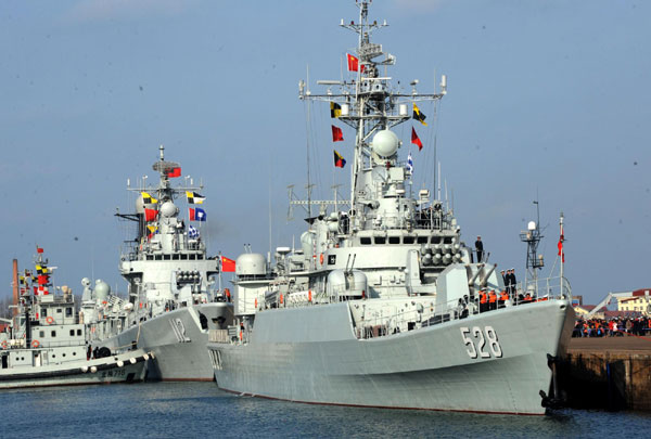 La frégate lance-missiles « Mianyang » (à droite) et le destroyer lance-missiles « Harbin » à l’ancre dans un port de la ville de Qingdao, dans la Province du Shandong, dans l'Est de la Chine le 16 février 2013, en direction du Golfe d'Aden et des eaux au large de la Somalie pour une mission d'escorte. La flottille, la 14e de son genre à être engagée dans des missions d'escorte, se compose d'un destroyer lance-missiles, une frégate et un navire de ravitaillement qui appartiennent tous à la Flotte de la Mer du Nord de la Marine de l’Armée Populaire de Libération (APL).