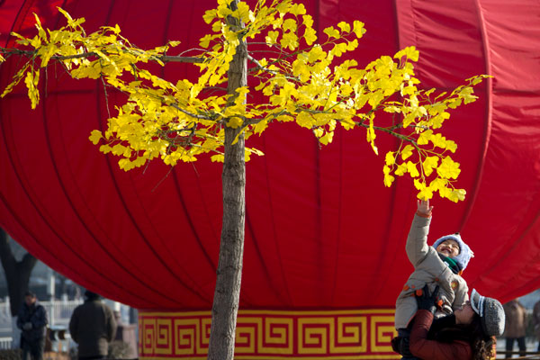 Le 26 janvier, à Beijing dans le district de Shunyi, un garçon et sa mère jouent sur une place ornée d'une énorme lanterne rouge. 