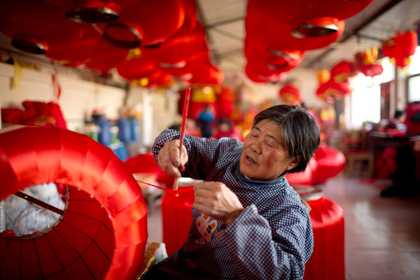 Le 26 janvier, dans le village de Hongmiao, situé à Beijing dans le district de Huairou, Yan Wanqin, âgée de 64 ans, brosse et colle un morceau de soie rouge. C'est est la plus ancienne ouvrière de l'atelier des lanternes du village. Photos par Kuang Linhua/China Daily 