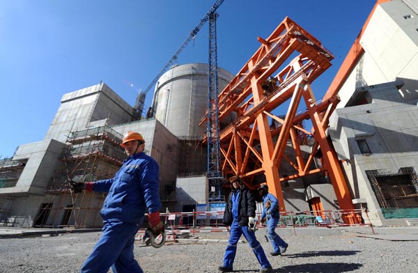 Le 19 février 2013, des membres du personnel passent devant une unité de production d'électricité en construction de la centrale nucléaire de Hongyanhe, se trouvant près de la ville de Wafangdian dans la province du Liaoning au nord-est de la Chine.[Photo/Xinhua]
