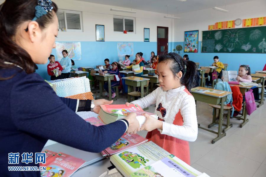 Lundi 25 janvier, à l'école primaire Chengguan du district autonome mongol de Hoboksar au Xinjiang, une maîtresse d'une classe de 4e année distribue les nouveaux manuels aux élèves. (Photo : Xinhua / Shadati)