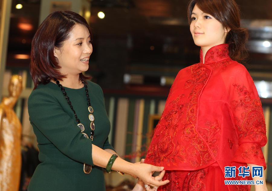 La styliste Guo Pei (à gauche) présente une robe de mariée de style chinois dans son magasin du n° 22 Waitan à Shanghai, dans l'Est de la Chine de l'est, le 2 mars 2013. [Photo / Xinhua]