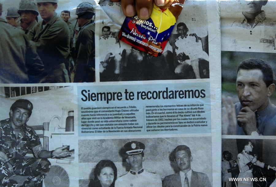 Une femme tient des photos de Hugo Chavez, le 6 mars 2013 à Caracas. (Xinhua/David de la Paz)