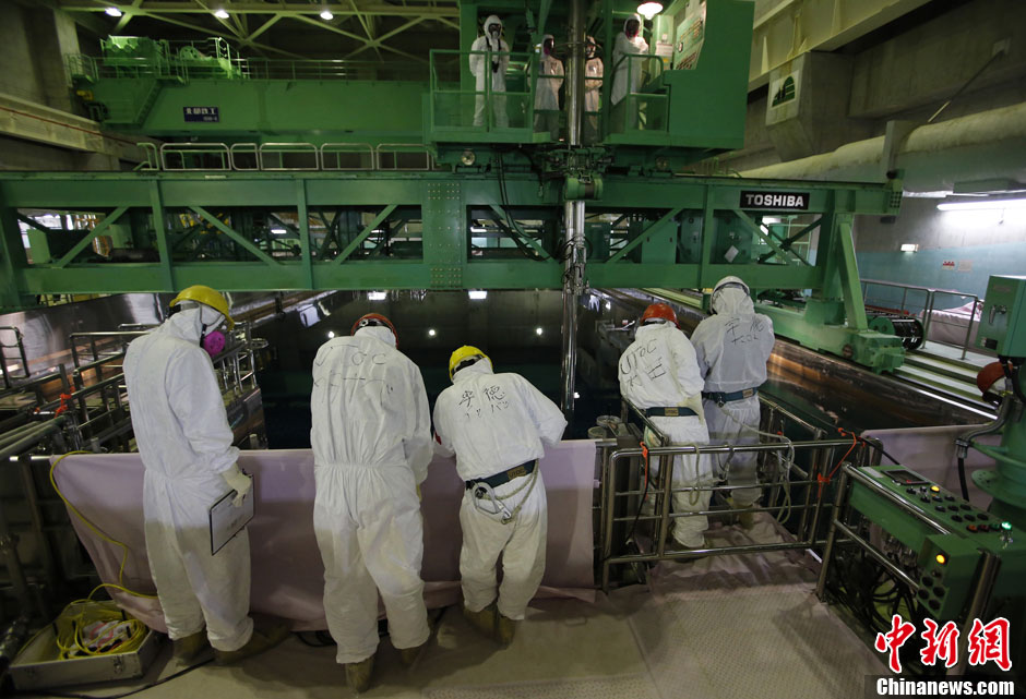 Des membres du personnel la Tokyo Electric Power Company conduisent des journalistes devant le réservoir de stockage des barres de combustible nucléaire.