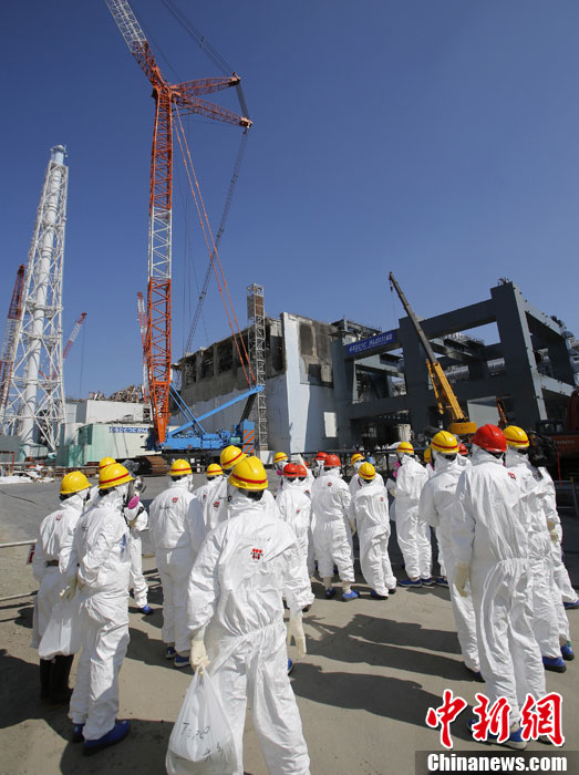 Des journalistes rassemblés devant les installations du réacteur n ° 4 de la centrale nucléaire Daiichi de Fukushima.