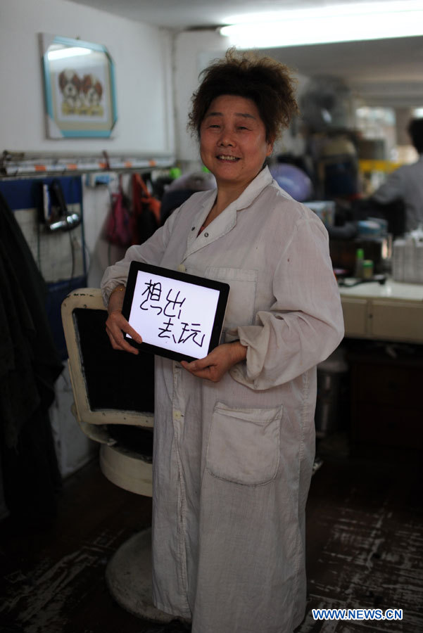 Mme Wu, coiffeuse âgée de 55 ans, souhaite un jour de congé pour la Journée de la femme, à Nanchang, capitale de la province orientale du Jiangxi, en Chine, le 7 mars 2013.