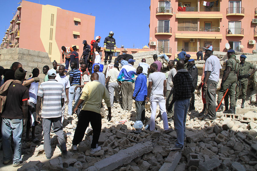 Des habitants locaux participent aux opérations de secours sur le site de l'effondrement d'un bâtiment à Dakar, capitale du Sénégal, le 8 mars 2013. Environ dix ouvriers ont été ensevelis dans les décombres d'un bâtiment et une enquête a été ouverte pour déterminer le nombre exact de victimes. (Photo : Tai Jianqiu)