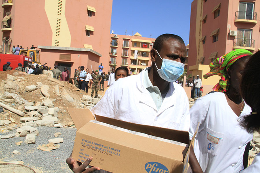Des travailleurs médicaux arrivent sur le site de l'effondrement d'un bâtiment à Dakar, capitale du Sénégal, le 8 mars 2013. Environ dix ouvriers ont été ensevelis dans les décombres d'un bâtiment et une enquête a été ouverte pour déterminer le nombre exact de victimes. (Photo : Tai Jianqiu)