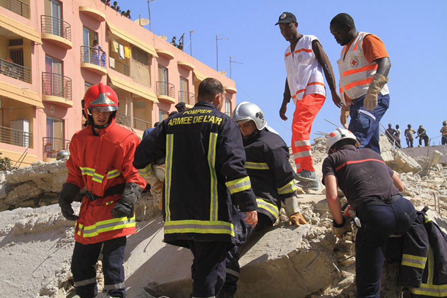 Les troupes françaises au Sénégal et les secouristes et travailleurs médicaux locaux participent aux opérations de secours sur le site de l'effondrement d'un bâtiment à Dakar, capitale du Sénégal, le 8 mars 2013. Environ dix ouvriers ont été ensevelis dans les décombres d'un bâtiment et une enquête a été ouverte pour déterminer le nombre exact de victimes. (Photo : Tai Jianqiu)