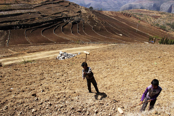 Le 16 mars 2013, deux enfants en plein travail, sur un domaine complètement aride du village de Zhongguan, (comté de Weining), dans la province du Guizhou, au sud-ouest de la Chine. [Photo/Xinhua]