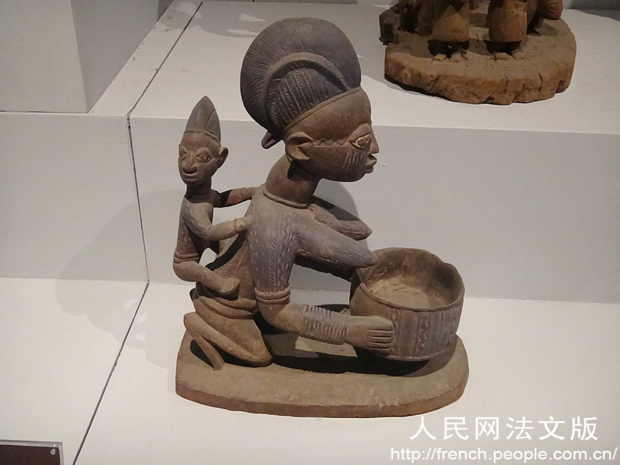 Une sculpture en bois d'une mère qui s'agenouille en portant son fils sur son dos, créée par l'ethnie Yoruba du Nigeria.