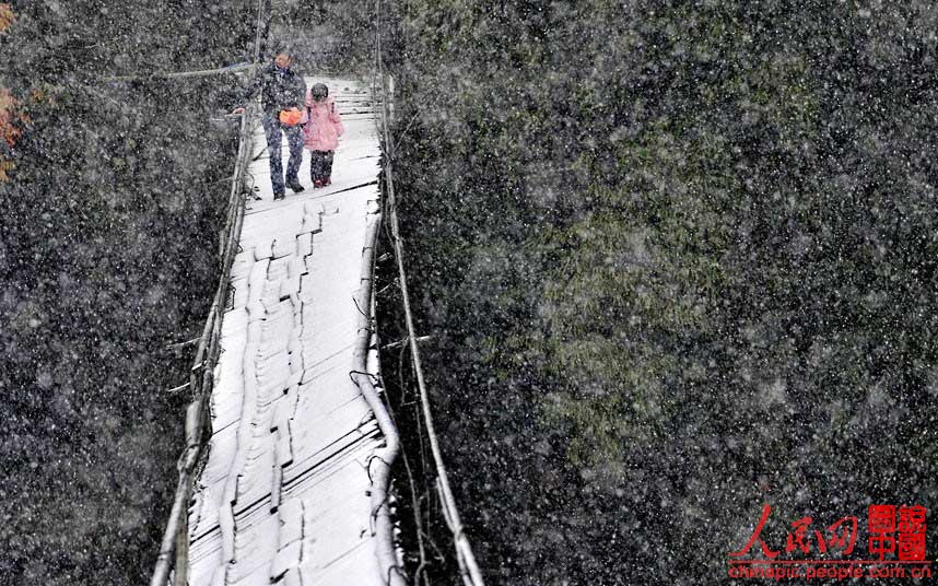 A Dujiangyan, dans la Province du Sichuan, une mère accompagne sa fille sous la neige pour une traversée dangereuse d'un pont de bois. Fortement endommagé par les intempéries, le pont de bois est devenu très instable et penche sur un côté.