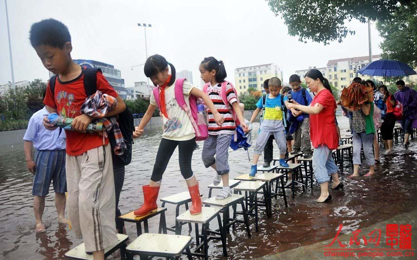 A Changzhou, dans la Province du Jiangsu après une tempête, les enfants traversent un pont de tabourets pour aller à l'école.