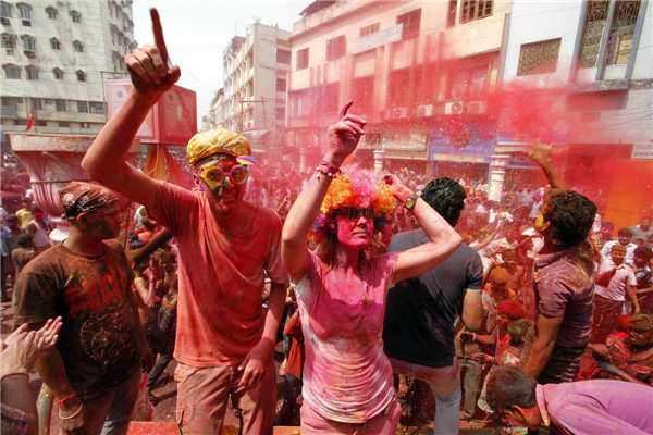 Des touristes étrangers barbouillés de couleurs fêtent Holi en dansant, dans la ville indienne de Guwahati, dans le Nord du pays, le 27 mars 2013. La Fête de Holi, également connue comme le Festival des Couleurs, annonce le début du printemps et est célébrée dans toute l'Inde. [Photo / Agences]