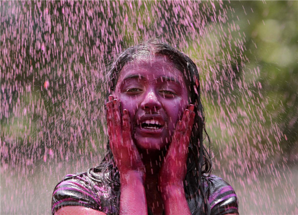 Une jeune fille sous une douche d'eau colorée, dans le cadre des célébrations de Holi dans la ville indienne d'Hyderabad, dans le Sud du pays, le 27 mars 2013. La Fête de Holi, également connue comme le Festival des Couleurs, annonce le début du printemps et est célébrée dans toute l'Inde. [Photo / Agences]