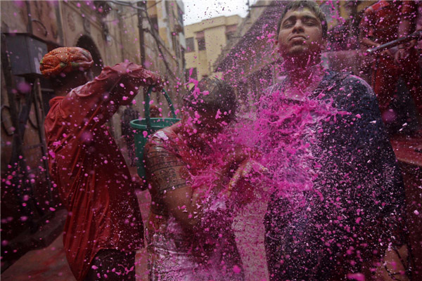 Des gens aspergent sur une femme d'eau colorée alors qu’elle marche dans une ruelle près du temple Bankey Bihari à Vrindavan lors des célébrations de Holi, dans l'Etat de l'Uttar Pradesh, dans le Sud de l’Inde, le 27 mars 2013. La Fête de Holi, également connue comme le Festival des Couleurs, annonce le début du printemps et est célébrée dans toute l'Inde. [Photo / Agences]