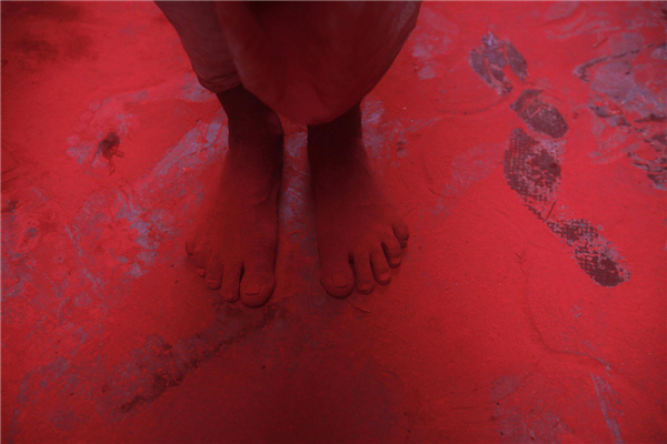 Les pieds d'un homme recouverts de poudre de couleur rouge, lors des célébrations de Holi dans une ruelle près du temple Bankey Bihari à Vrindavan, dans l'État indien de l'Uttar Pradesh, le 27 mars 2013. La Fête de Holi, également connue comme le Festival des Couleurs, annonce le début du printemps et est célébrée dans toute l'Inde. [Photo / Agences]