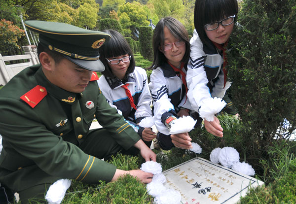 Les étudiants et les soldats offrent des fleurs pour honorer les martyrs de la Révolution dans la ville de Taizhou, dans la Province du Zhejiang, le 27 mars 2013, à quelques jours de la Fête de Qingming, ou Journée de Balayage des Tombes, qui tombe cette année le 4 avril. Cette journée est une fête nationale lors de laquelle on honore et on se souvient de ses proches défunts dans les cimetières et les monuments commémoratifs. [Photo Jia Ce / Asianewsphoto]