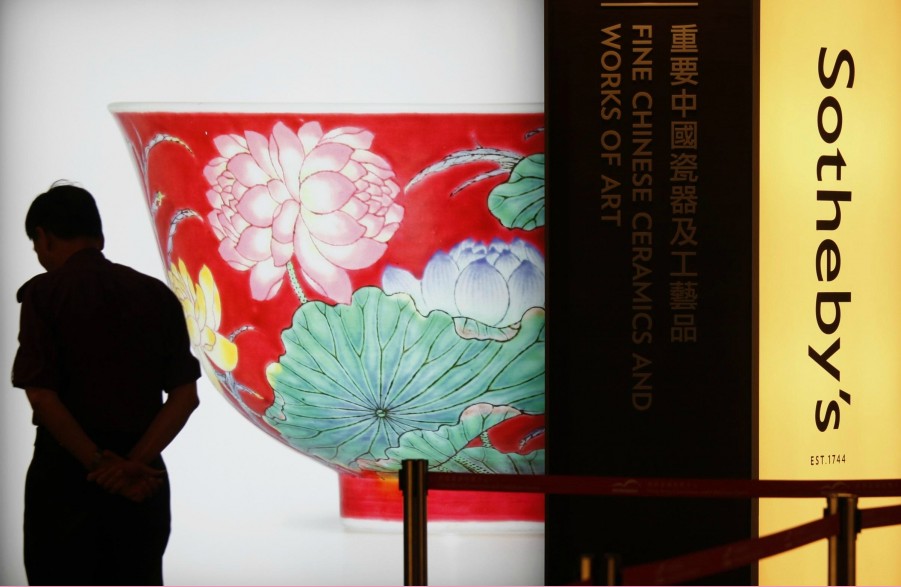 Le 2 avril 2013, un agent de sécurité passe devant l'affiche d'un bol falangcai, d'une couleur rubis et à double lotus, datant du règne de l'empereur Kangxi de la dynastie des Qing, lors de la présentation préliminaire organisée par Sotheby's à Hong Kong. (Photo : Agences)