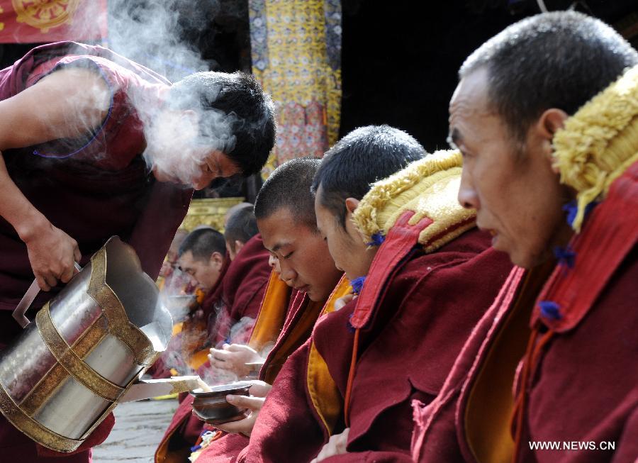 Des boissons sont proposées aux moines lors de la cérémonie de la soutenance des thèses du Gexe Lharampa, le plus haut diplôme universitaire pour l'étude du bouddhisme tibétain, au temple de Jokhang à Lhassa, capitale de la région autonome du Tibet, dans le sud-ouest de la Chine, le 5 avril 2013.