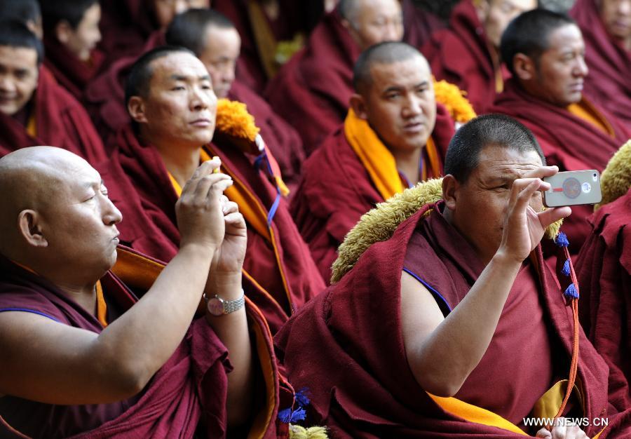 Des moines prennent des photos lors de la cérémonie pour soutenir les thèses du Gexe Lharampa, le plus haut diplôme universitaire pour l'étude du bouddhisme tibétain, au Temple de Jokhang à Lhassa, capitale de la région autonome du Tibet, dans le sud-ouest de la Chine, le 5 avril 2013.