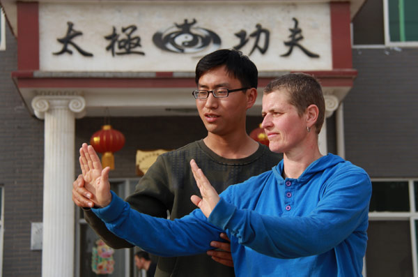 Le professeur de tai ji quan, Chen Zhiwei, aide une jeune étrangère pour pratiquer cet art martial dans une école de wushu dans le Henan, le 8 avril 2013. [Photo/Asianewsphoto]