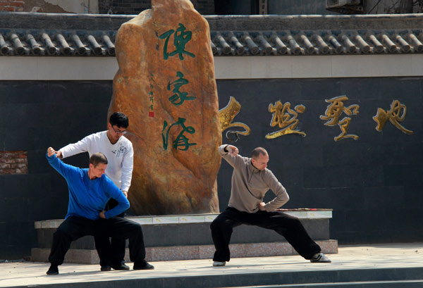 Le professeur de tai ji quan, Chen Zhiwei, instruit deux visiteurs étrangers dans une école privée de wushu dans le comté de Wenxian, berceau des arts martiaux dans le centre de la Chine, la province du Henan, le 8 avril 2013. Des milliers d'étrangers visitent le comté chaque année pour apprendre le tai ji quan. A noter que plus de 200 millions de personnes pratiquent cet art ancestral à travers le monde. [Photo/Asianewsphoto]