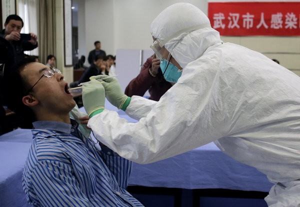 Un employé des services sanitaires recueille un échantillon de salive de la grippe aviaire sur un « patient » pour procéder à des tests, lors d’un exercice de simulation de l'infection humaine au virus de la grippe aviaire H7N9 à Wuhan, dans la Province du Hubei, dans le centre de la Chine, le 8 avril, 2013. [Photo / CFP]