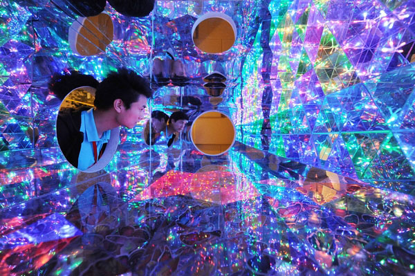 Un employé d’un musée de Shanghai vérifie une « boîte magique » en panneaux en plastique transparents qui reflètent des lumières colorées pour créer une merveille optique éblouissante. [Photo par Lai Xinlin / Pour le China Daily]