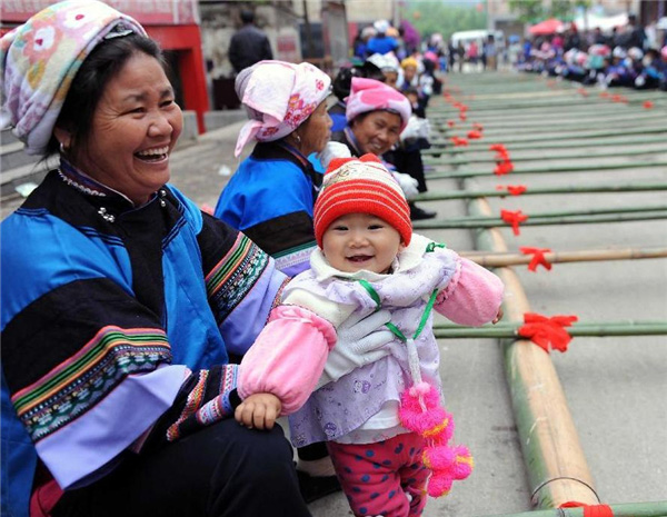 Une femme de l'ethnie Dai regarde un spectacle avec son petit-fils lors du festival de la culture et des coutumes folkloriques marquant le « San Yue San » (le troisième jour du troisième mois lunaire du calendrier chinois) dans le Comté de Shizong, dans la Province du Yunnan, dans le Sud-ouest de la Chine, le 12 avril 2013. La Fête du San Yue San, qui attire des dizaines de milliers d’habitants locaux et les touristes venant à la fois de Chine et de l'étranger, a eu lieu ici vendredi. [Photo / Xinhua]
