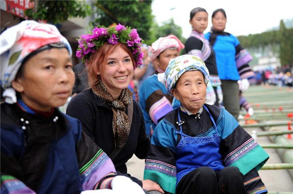 Une jeune française (au centre, devant) pose pour une photo de groupe avec des femmes de l'ethnie Dai lors du festival de la culture et des coutumes folkloriques marquant le « San Yue San » (le troisième jour du troisième mois lunaire du calendrier chinois) dans le Comté de Shizong, dans la Province du Yunnan, dans le Sud-ouest de la Chine, le 12 avril 2013. La Fête du San Yue San, qui attire des dizaines de milliers d’habitants locaux et les touristes venant à la fois de Chine et de l'étranger, a eu lieu ici vendredi. [Photo / Xinhua]