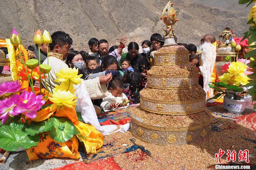 Le 14 avril 2013, des habitants locaux du bourg de Jiegu répandent des graines de riz colorées, symbole du bonheur, sur une petite tour pendant la cérémonie d'hommage. (Photo : Hu Guilong )
