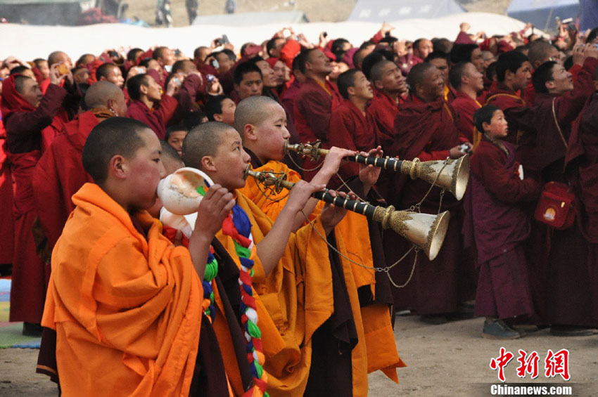 Le 14 avril 2013, quatre jeunes moines jouent des instruments musicaux religieux devant le thangka étalé sur la pente. (Photo : Hu Guilong )